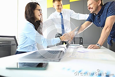 Businessmen and businesswoman in their office smiling and shaking hands Stock Photo