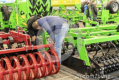 Businessmen are considering agricultural machinery at an exhibition Editorial Stock Photo