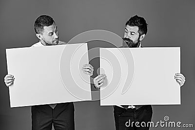 Businessmen with curious faces present green and pink sign boards Stock Photo