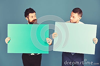 Businessmen with curious faces present green and pink sign boards Stock Photo