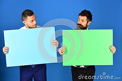 Businessmen with curious faces present green and pink sign boards Stock Photo