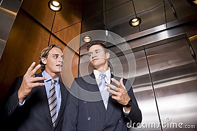 Businessmen in elevator conversing Stock Photo