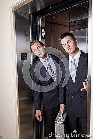 Businessmen in elevator looking out doorway Stock Photo