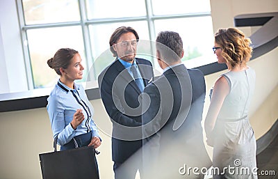 Businessmen greeting while standing with colleagues at reception lobby in office Stock Photo