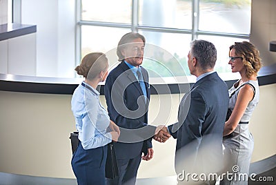 Businessmen greeting while standing with colleagues at reception lobby in office Stock Photo