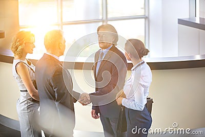 Businessmen greeting while standing with colleagues at reception lobby in office Stock Photo