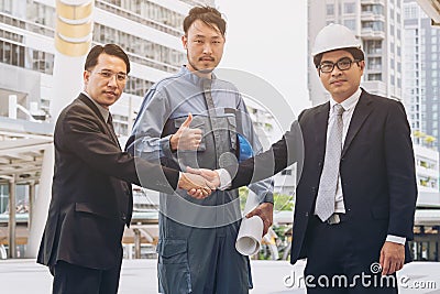 Businessmen handshake with engineer thumbs up Stock Photo