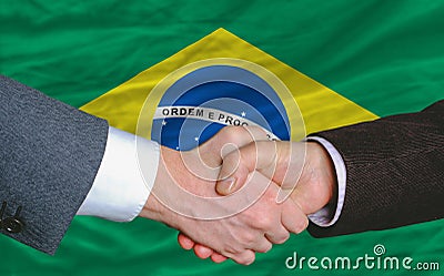 Businessmen handshake in front of brazil flag Stock Photo