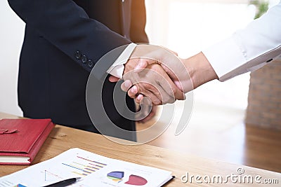 Businessmen join hands to invest and share profits in real estate projects. On the table, there are documents and historical Stock Photo