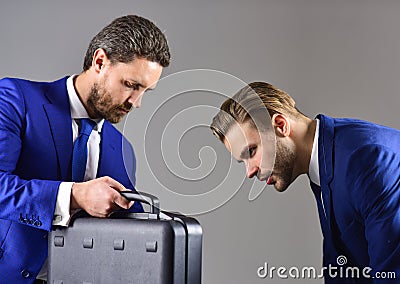 Businessmen look into opened black briefcase on dark background. Stock Photo