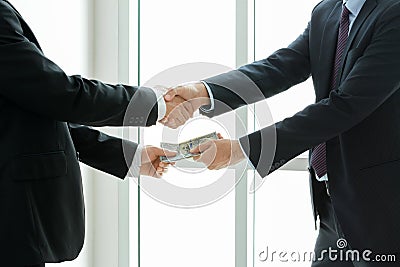 Businessmen making handshake while passing money Stock Photo