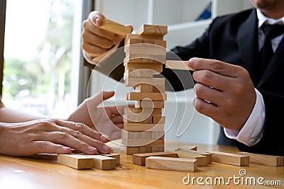 Businessmen picking wood blocks to fill the missing wood blocks and protect wood blocks to fail. Growing business concept Stock Photo