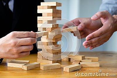 Businessmen picking wood blocks to fill the missing wood blocks and protect wood blocks to fail. Growing business concept Stock Photo