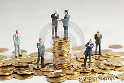 Businessmen shake hands as a symbol of a successful profitable transaction. Businessmen on a stack of gold coins as a symbol of Stock Photo