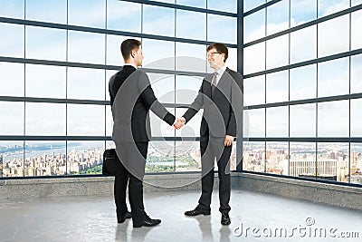 Businessmen shake hands in empty loft room Stock Photo