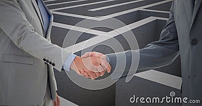 Businessmen shaking hands against maze in background Stock Photo