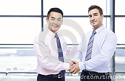 Businessmen shaking hands at airport Stock Photo