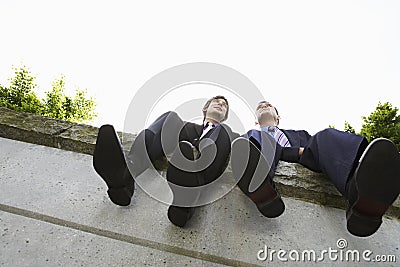 Businessmen Sitting Side By Side On Wall Stock Photo
