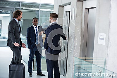 Businessmen talking while waiting for elevator Stock Photo