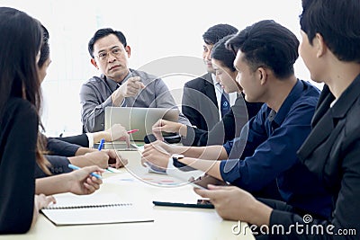 Businesspeople at conference, seriously senior businessman pointing at someone to answer question at group meeting. Elderly boss Stock Photo