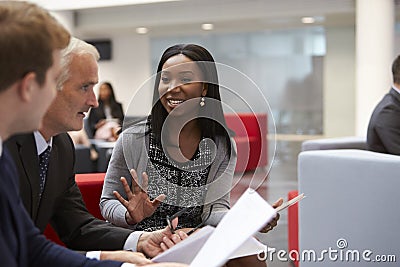 Businesspeople Discuss Document In Lobby Of Modern Office Stock Photo