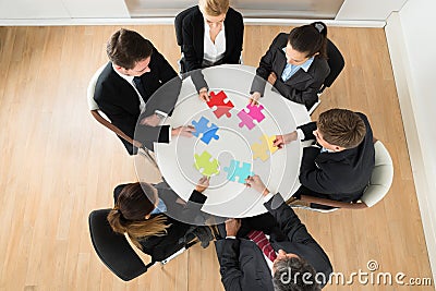 Businesspeople holding multi-colored jigsaw puzzle Stock Photo