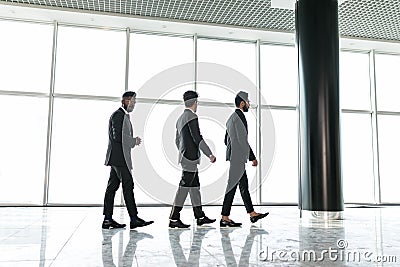 Businesspeople moving along the corridor with big panoramic windows Stock Photo