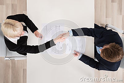 Businesspeople Shaking Hand At Desk Stock Photo