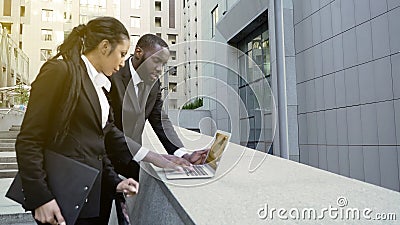 Businesspeople standing in street with laptop, talking, negotiations preparation Stock Photo