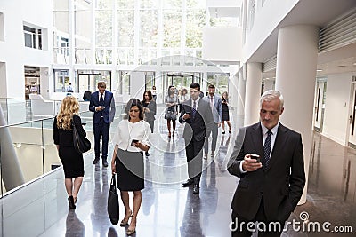 Businesspeople Using Technology In Busy Lobby Area Of Office Stock Photo