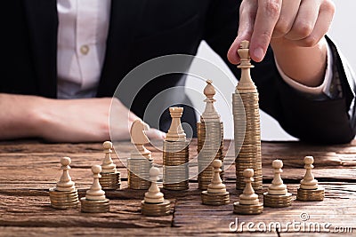 Businessperson Arranging Chess Piece On Stacked Coins Stock Photo