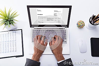 Businessperson Checking Invoice On Laptop Stock Photo