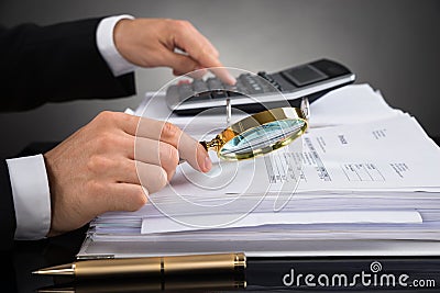 Businessperson Checking Invoice With Magnifying Glass Stock Photo