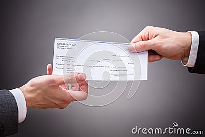 Businessperson Giving Cheque To Colleague Stock Photo