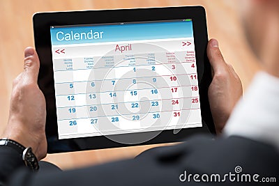 Businessperson Looking At Calendar On Digital Tablet Stock Photo