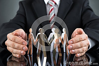 Businessperson Protecting Cutout Figures Stock Photo