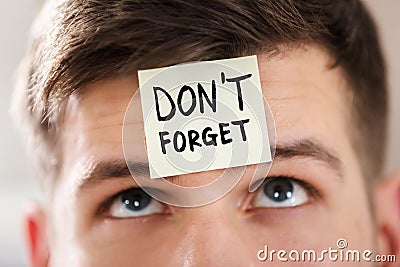 Sticky Note With Don`t Forget Text Stuck On Man`s Forehead Stock Photo