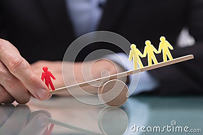 Businessperson Showing Imbalance Between Figures On Seesaw Stock Photo