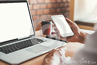 Businesss man using laptop and Mobile Phone with blank screen in the office Stock Photo