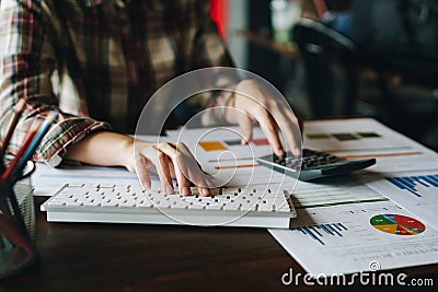 Businesswoman analyzing financial reports with calculator and typing on modern computer keyboard at office. Business analytics Stock Photo