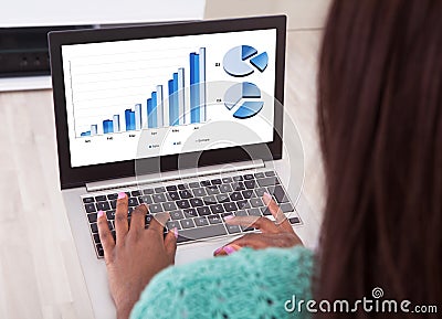 Businesswoman analyzing graphs on laptop at home Stock Photo