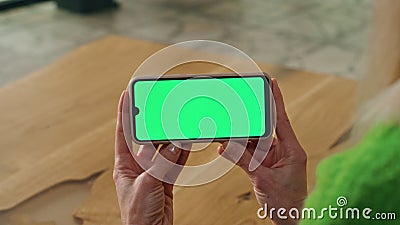 Businesswoman arms holding mockup smartphone indoors. Lady using green cellphone Stock Photo