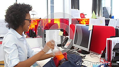 Businesswoman Arriving In Office And Sitting At Desk. Businesswoman arrives at office - unpacks bag before sitting at desk and talking to male colleague.Shot on Businesswoman Arriving In Office And Sitting At Desk. Businesswoman arrives at office - unpacks bag before sitting at desk and talking to male colleague.Shot on