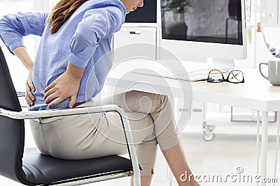 Businesswoman with back pain in office Stock Photo