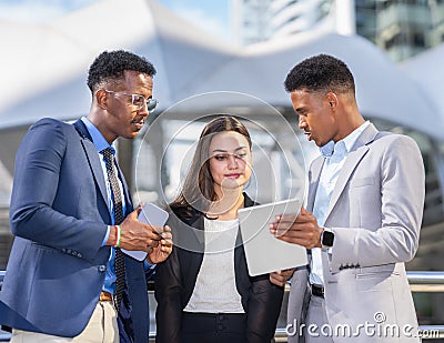 businesswoman in black suit working with black executive man in blue suit and businessman in grey suit. Stock Photo