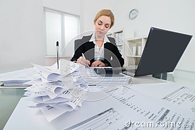 Businesswoman Calculating Invoice At Desk Stock Photo