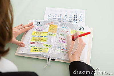 Businesswoman With Calendar Writing Schedule In Diary Stock Photo