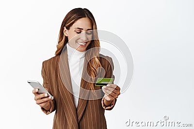 Businesswoman with credit card and smartphone making payment, using online shopping app, purchase with mobile phone Stock Photo