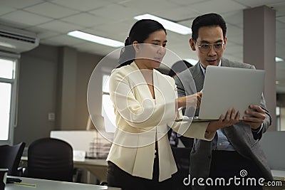 Businesswoman discuss with Businessman in office about job project both of them holding laptop lady point her finger to laptop Stock Photo