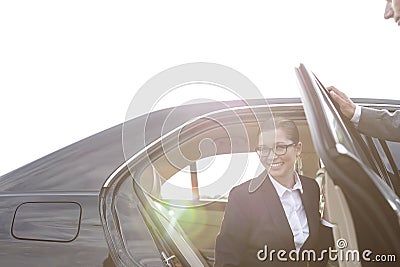 Businesswoman disembarking from car by colleague against sky Stock Photo